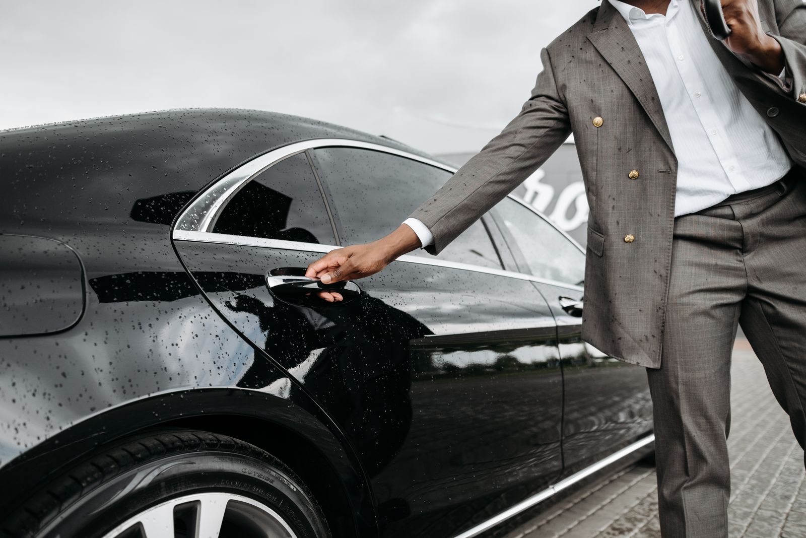 Chauffeur in a suit opening the door of a black executive car